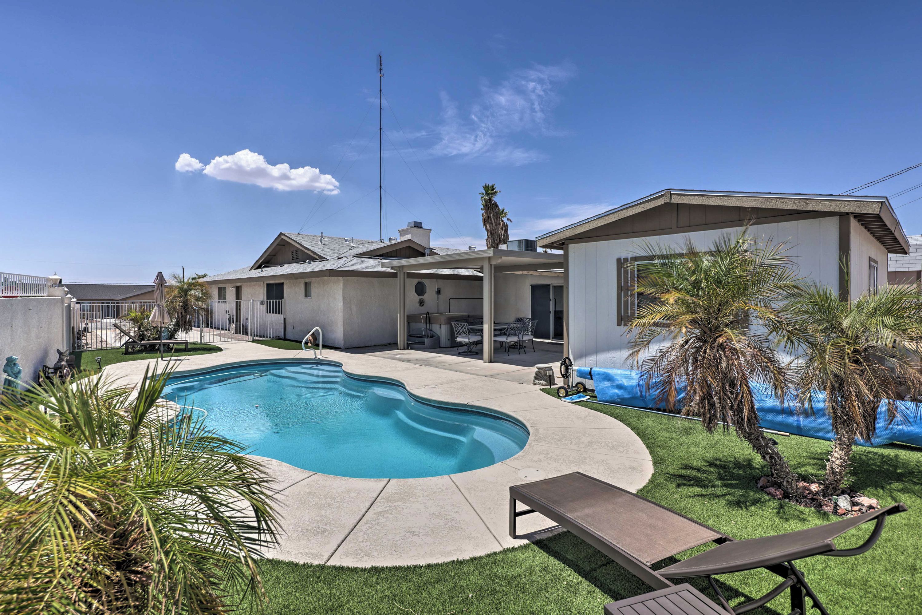 Ein Wohngrundstück mit Schwimmbad, überdachter Terrasse und Rasenfläche.