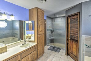 Een badkamer met een grote spiegel, een houten wastafelmeubel en een douche met een glazen deur.
