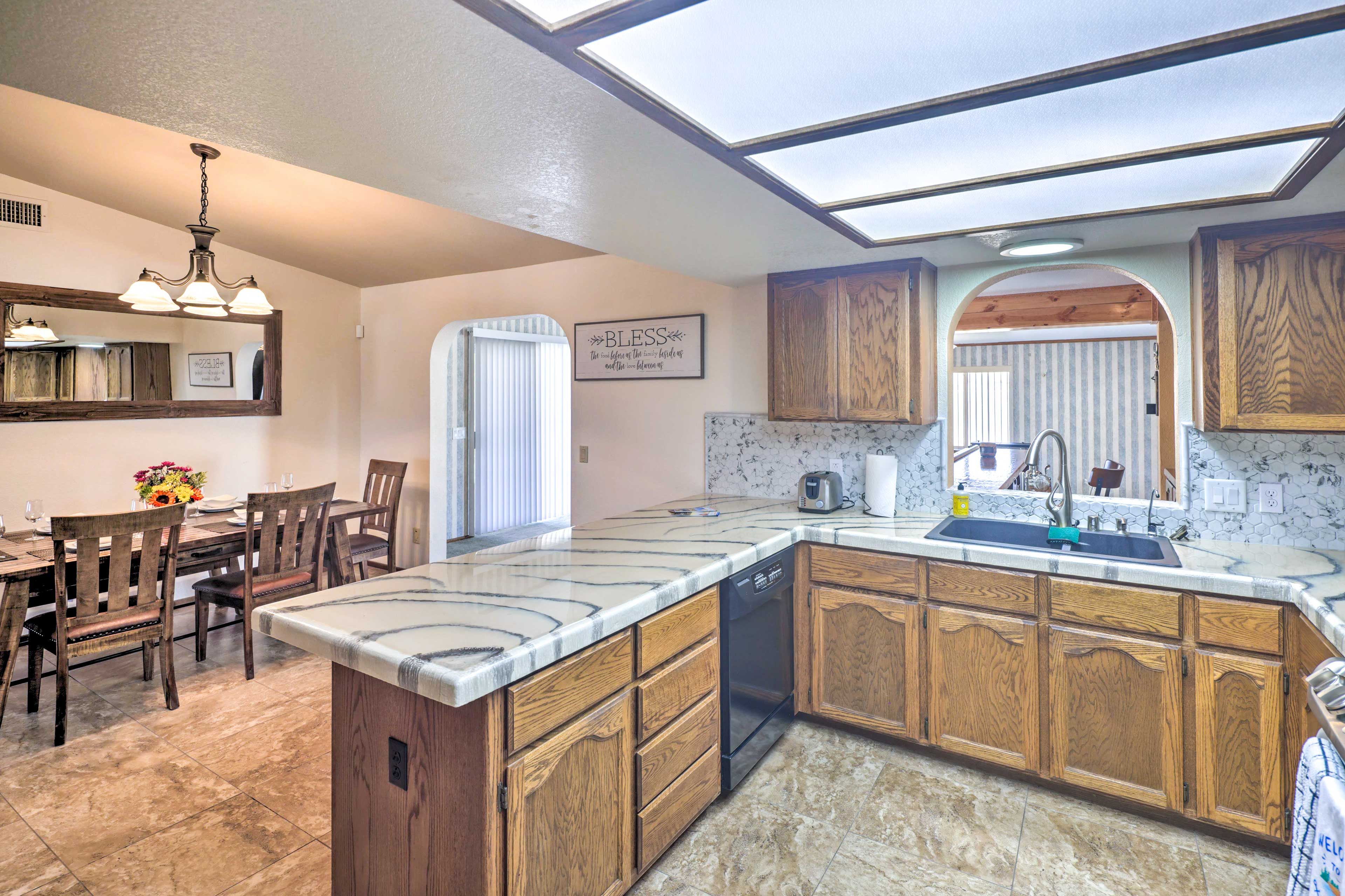 A kitchen with a central island, wooden cabinets, a dishwasher, and a dining area with chairs and a table.