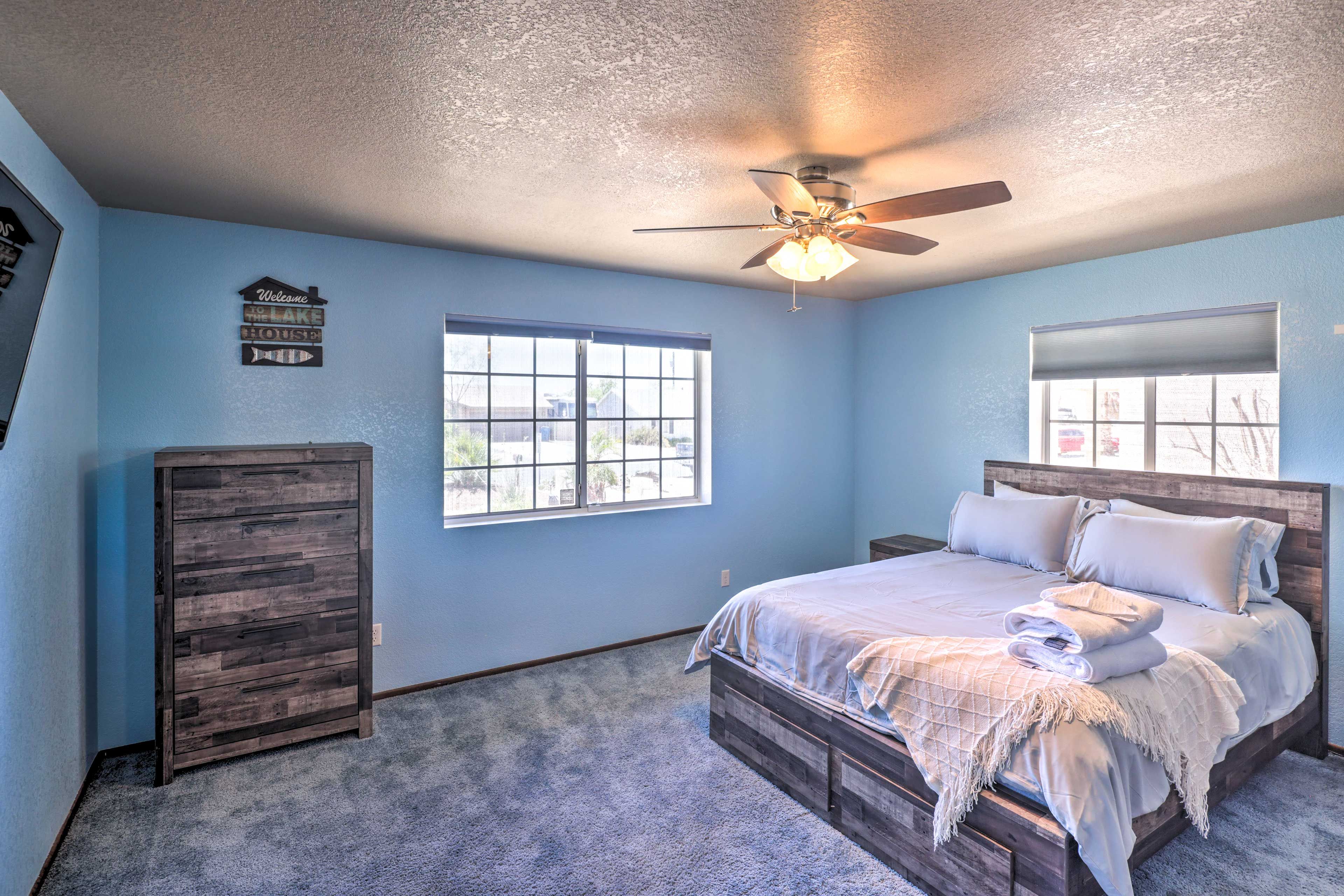 A bedroom with a bed, a ceiling fan, a window, and a dresser.