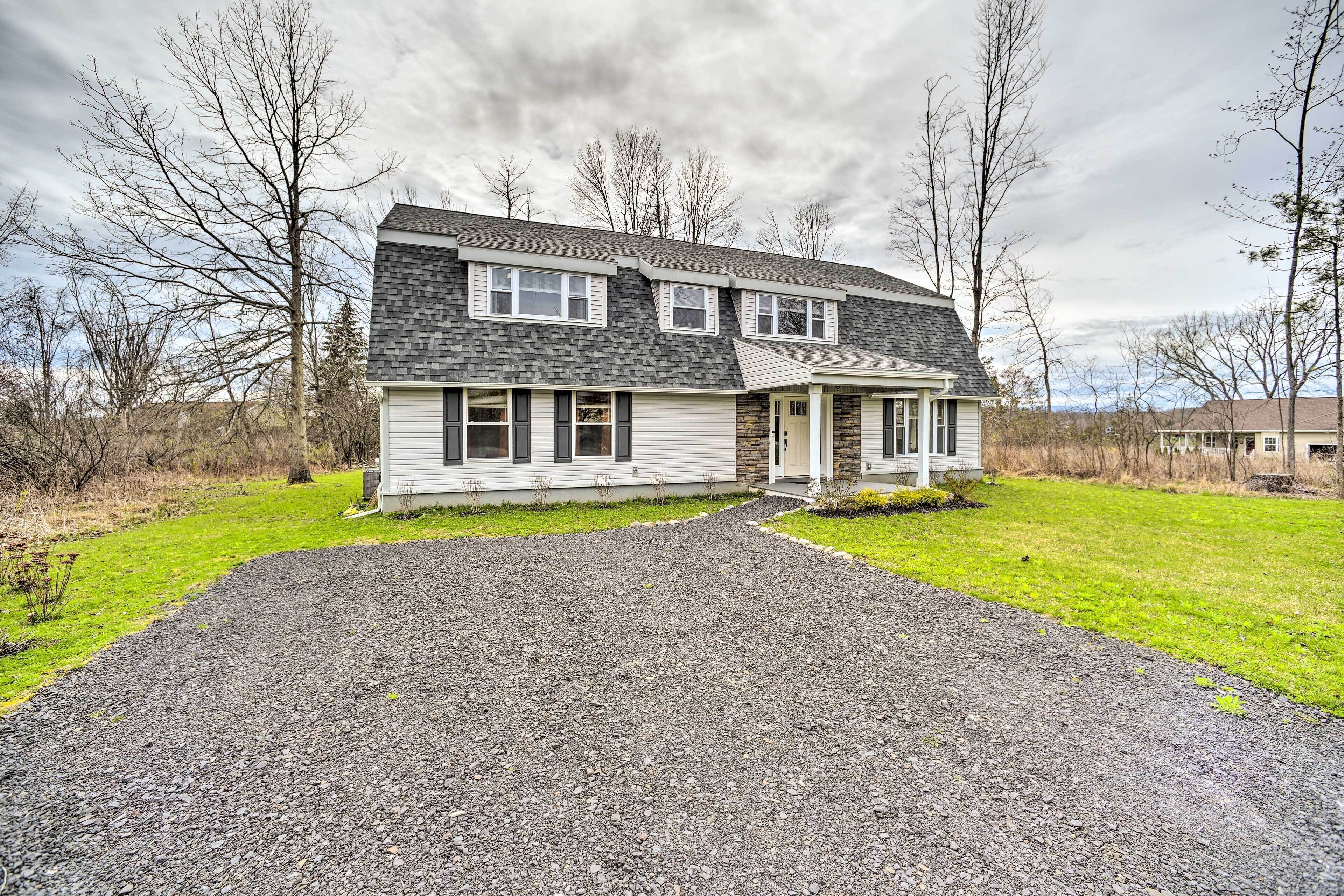A two-story house with a gravel driveway and a front porch.