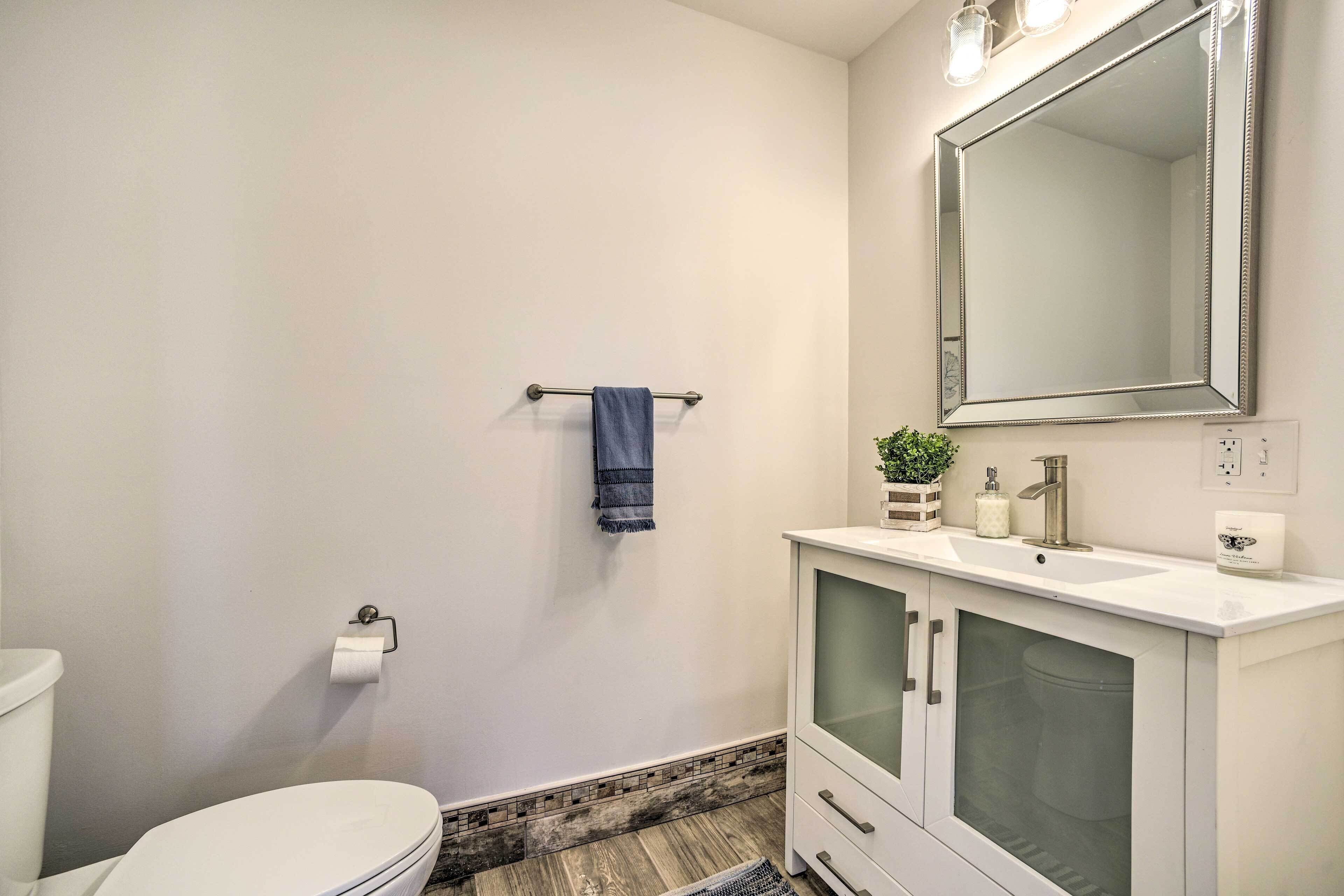 A bathroom with a toilet, a sink with a mirror above it, and a towel rack with a towel.