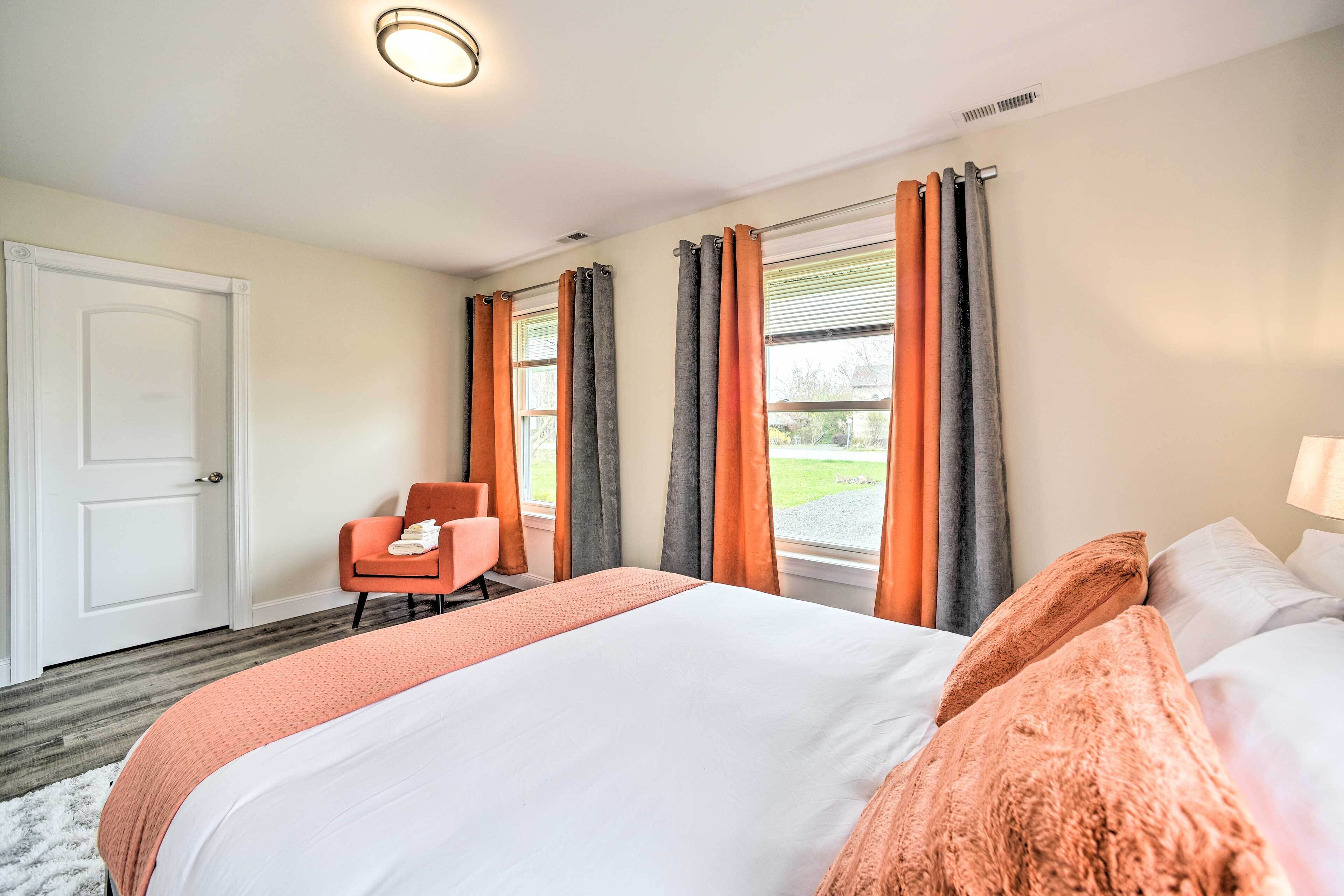 Une chambre d’hôtel avec un grand lit, une chaise et une fenêtre avec des rideaux.