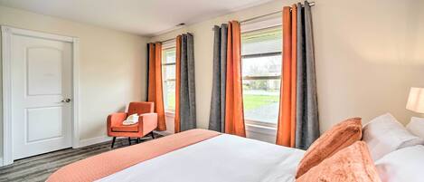 Une chambre d’hôtel avec un grand lit, une chaise et une fenêtre avec des rideaux.