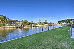 A waterfront property with a grassy area, a dock, and residential buildings.