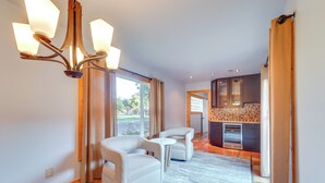 A spacious living area with a modern chandelier, two white armchairs, a small round table, and a kitchen in the background. - Lovely Lubbock Home w/ Furnished Deck & Grill (Lubbock)
