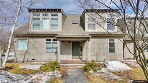 A two-story house with a front porch, a driveway, and a snow-covered yard.