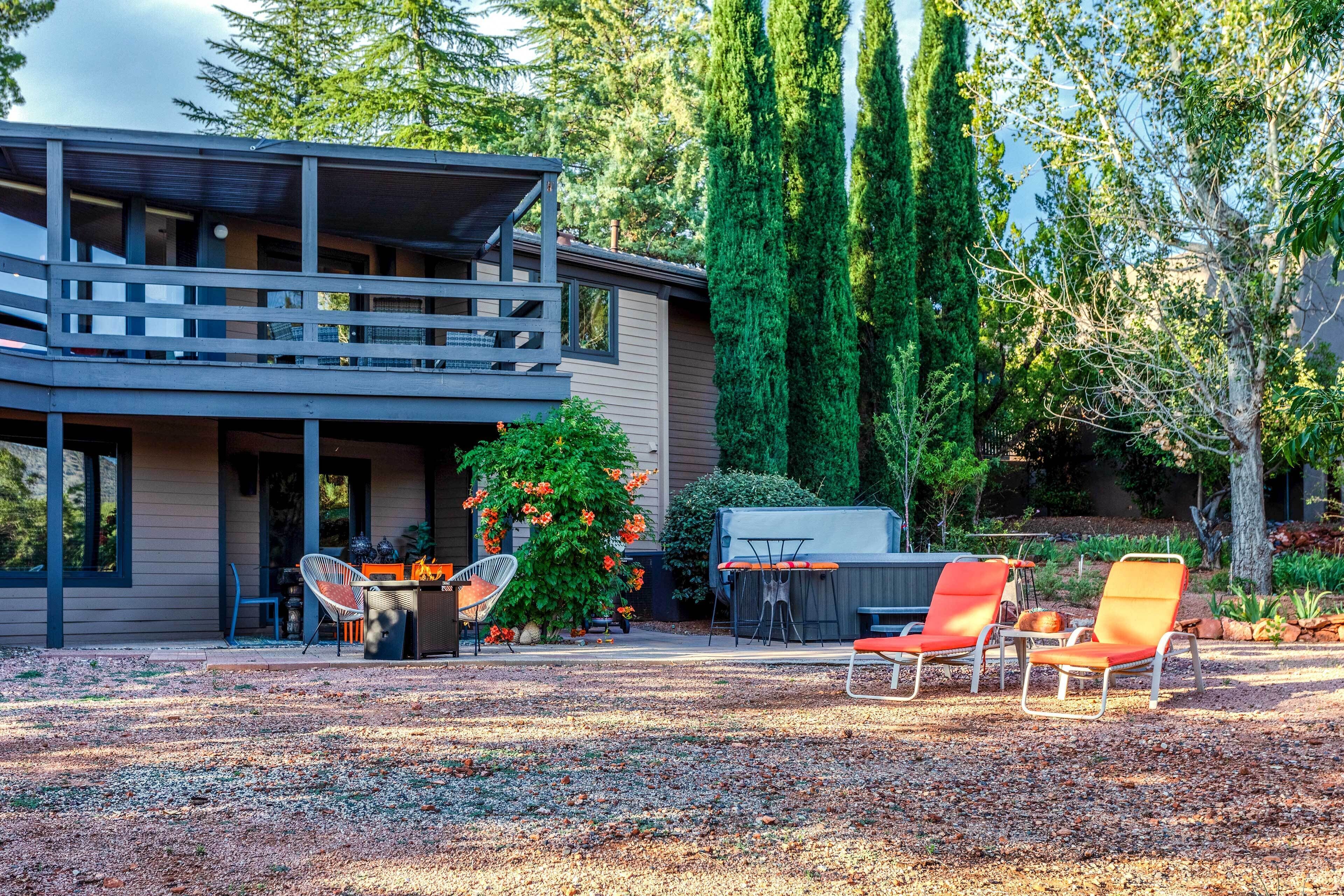 A modern two-story house with a balcony, outdoor seating area, and a well-maintained garden.