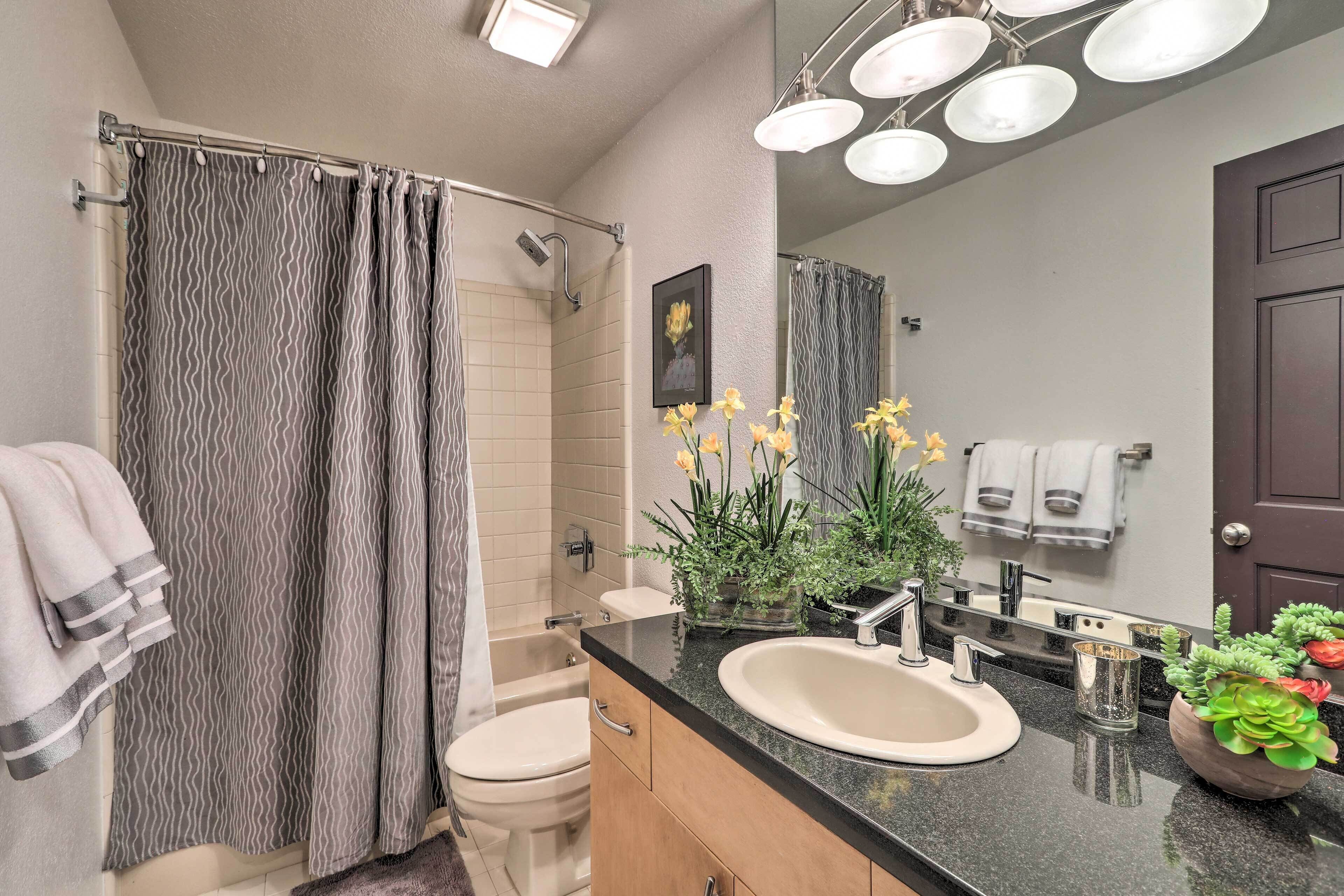 Une salle de bain équipée d’un rideau de douche, de toilettes, d’un lavabo et d’un miroir.