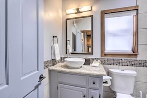 Een badkamer met een wit wastafel, spiegel, toilet en douche.