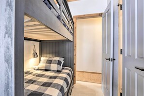 Een slaapkamer met een stapelbed, een bedlampje en een deur naar een andere kamer.