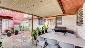 A covered patio with a table and chairs, a grill, and potted plants. - Corpus Christi Extended Stay - 7 Mi to Beach! (Corpus Christi)
