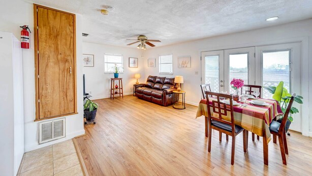 A spacious living area with a wooden floor, a leather sofa, a dining table set for four, and a ceiling fan. - Corpus Christi Extended Stay - 7 Mi to Beach! (Corpus Christi)