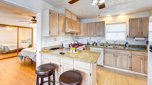 A compact kitchen with wooden cabinets, a granite countertop, and a ceiling fan. - Corpus Christi Extended Stay - 7 Mi to Beach! (Corpus Christi)