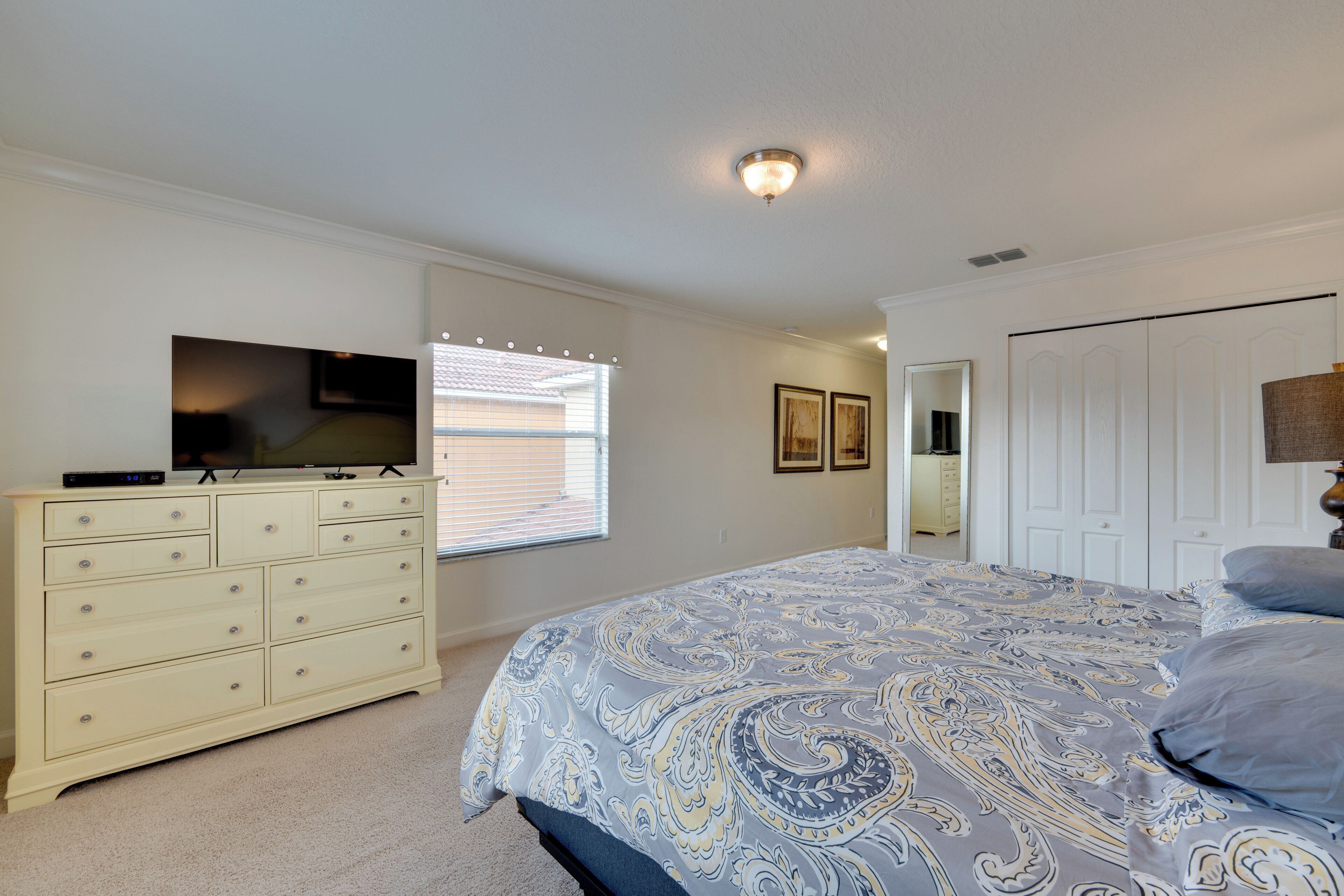 Un dormitorio con cama, cómoda, televisión y puerta.