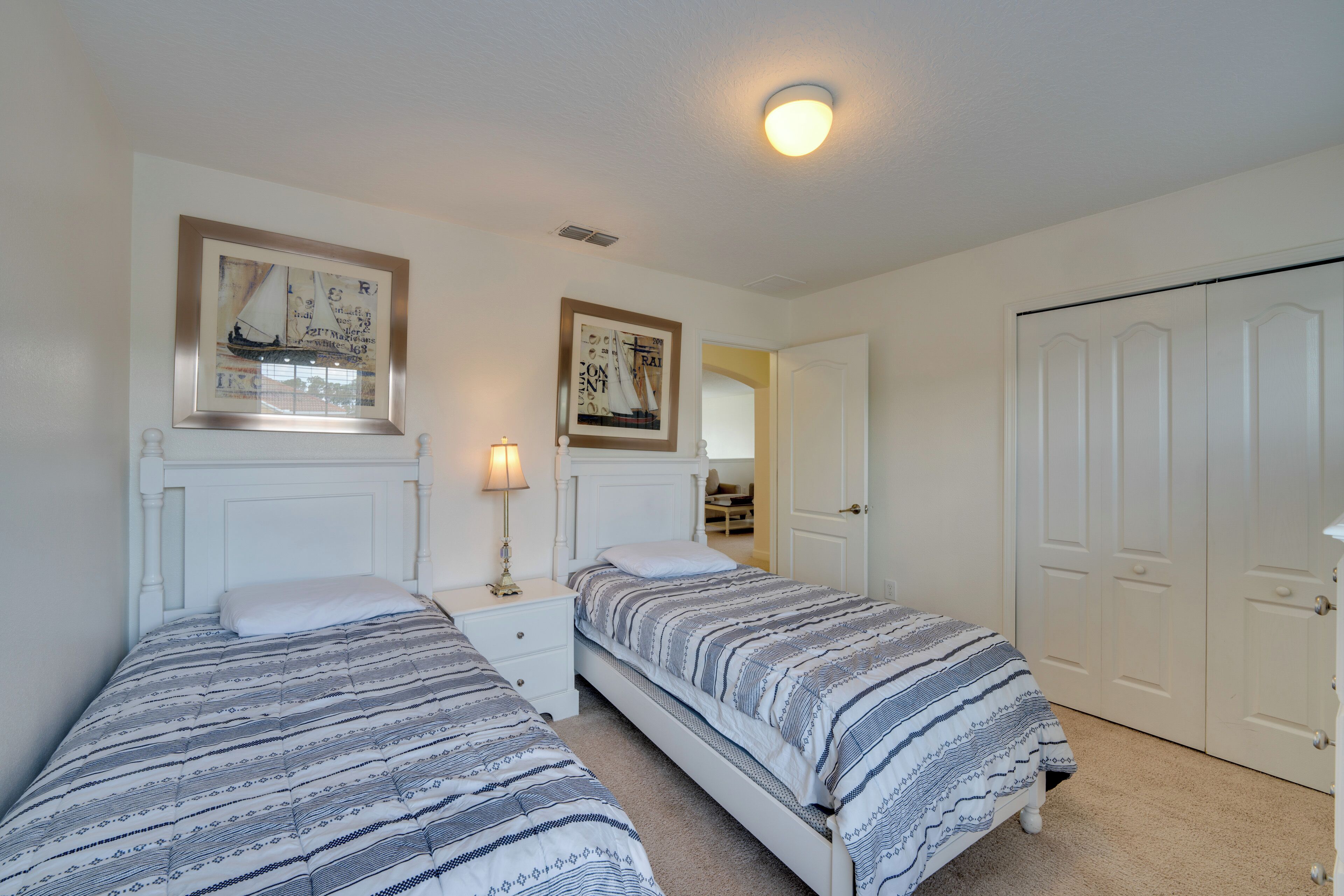 A bedroom with two beds, a nightstand, a lamp, and a door.