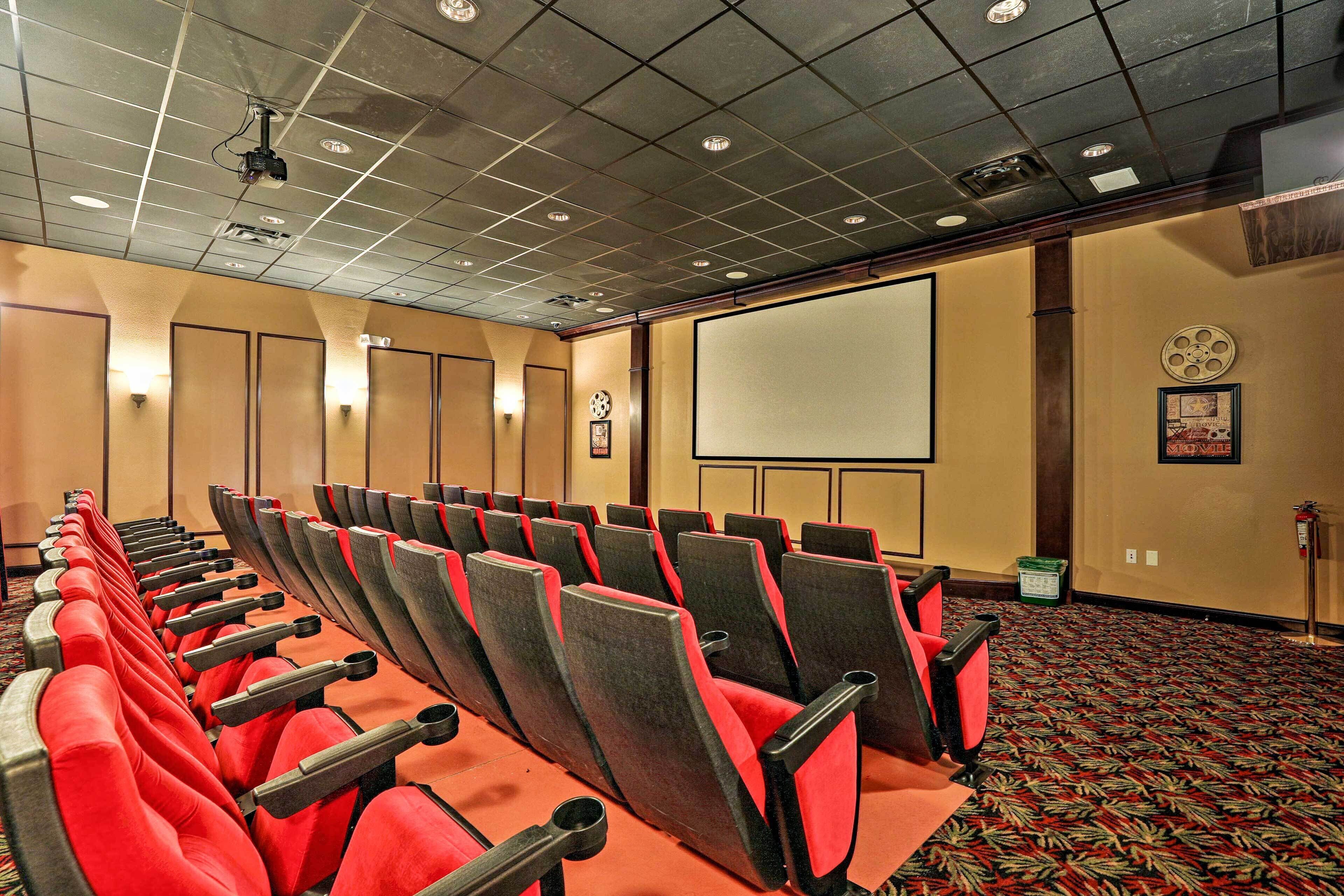 A conference room with rows of chairs, a projector, and a screen.