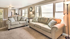 A living room with two sofas and a coffee table, a clock on the wall, and a view of a lake through large windows. - Pine River Lake Home w/ Boat & Kayak Rentals! (Pine River)