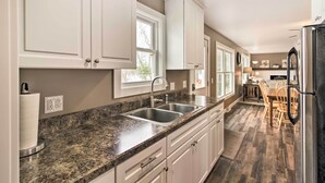 A modern kitchen with granite countertops, white cabinets, and a stainless steel sink. - Pine River Lake Home w/ Boat & Kayak Rentals! (Pine River)