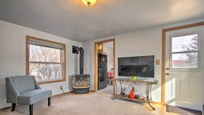 A living room with a sofa, a fireplace, a TV, and a door. - Pet-friendly Malta Home Near Hunting Areas! (Malta)