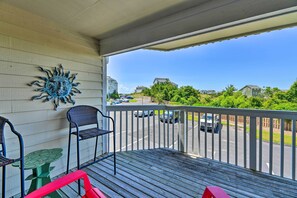 A wooden deck with a railing, a metal sun decoration, and a green table with two chairs. - Point Emerald Resort Retreat: Walk to Beach! (Emerald Isle)
