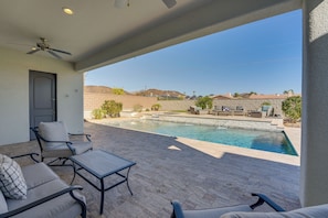 A covered patio with a pool, outdoor furniture, and a view of the surrounding landscape.