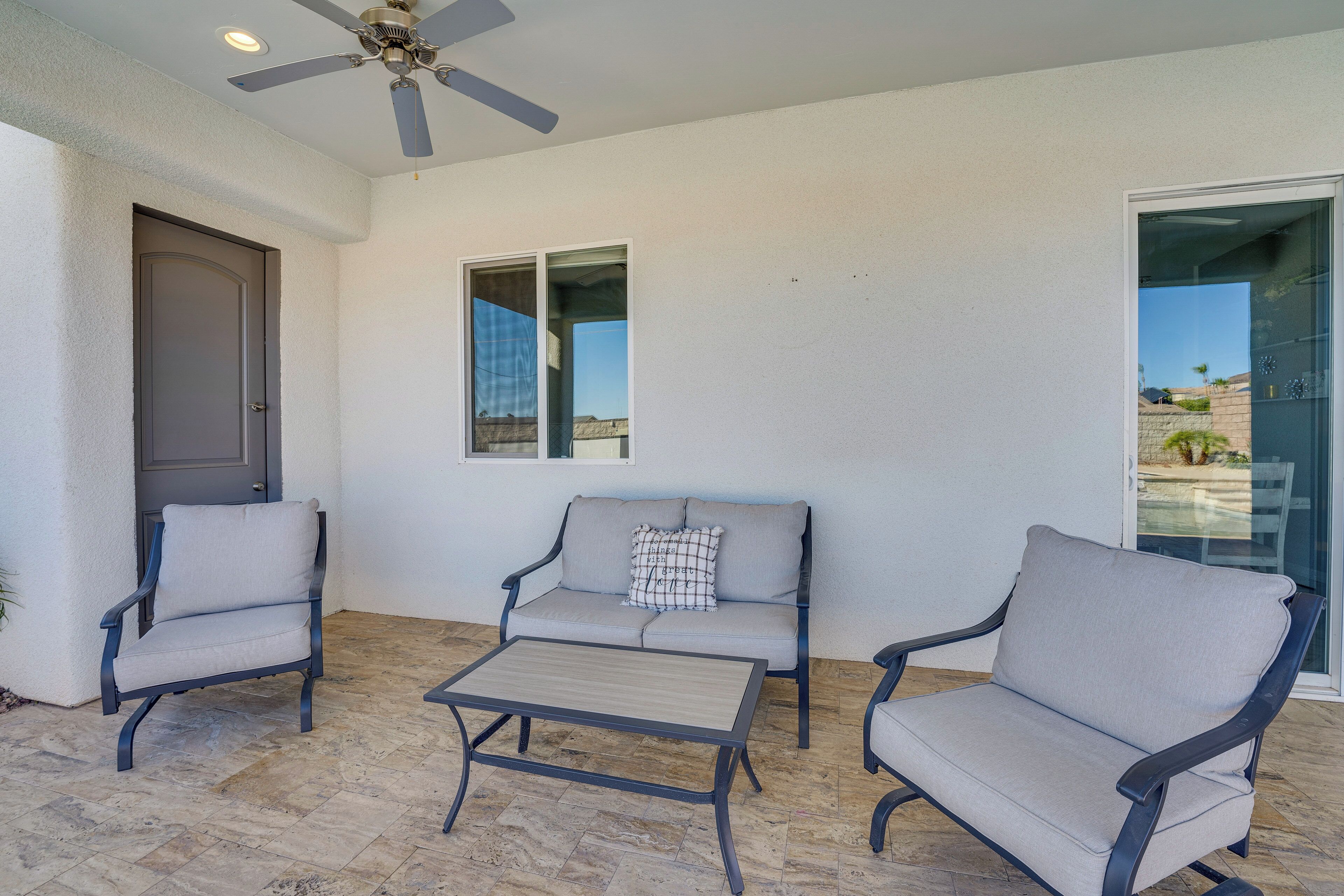 A patio area with a ceiling fan, a sofa, two armchairs, and a coffee table.