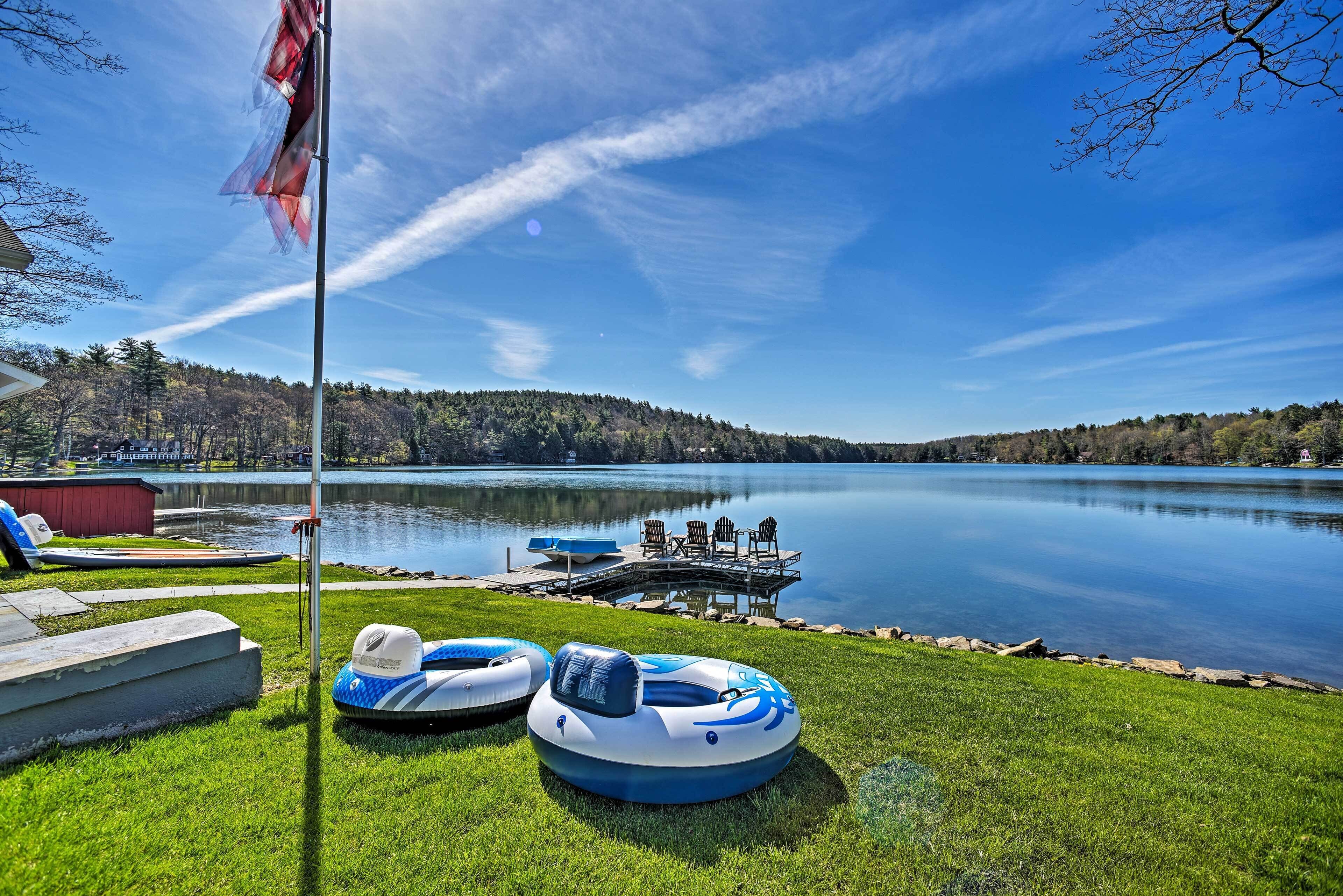 A lakeside deck with inflatable rafts, a dock, and a flagpole.