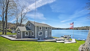 Et toetagers hus med en anløbsbro og et flagstang, der kigger ud over en sø.