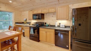 A modern kitchen with wooden cabinets, stainless steel appliances, and a dining area with a table and chairs. - Cozy Apt w/ Deck, ~ 5 Miles to Acadia Nat'l Park! (Northeast Harbor)