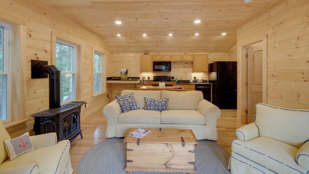 A cozy cabin interior with a wooden interior, a sofa, a coffee table, and a kitchen area. - Cozy Apt w/ Deck, ~ 5 Miles to Acadia Nat'l Park! (Northeast Harbor)