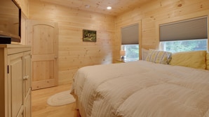A wooden cabin bedroom with a bed, a door, a window with blinds, and a small picture on the wall. - Cozy Apt w/ Deck, ~ 5 Miles to Acadia Nat'l Park! (Northeast Harbor)