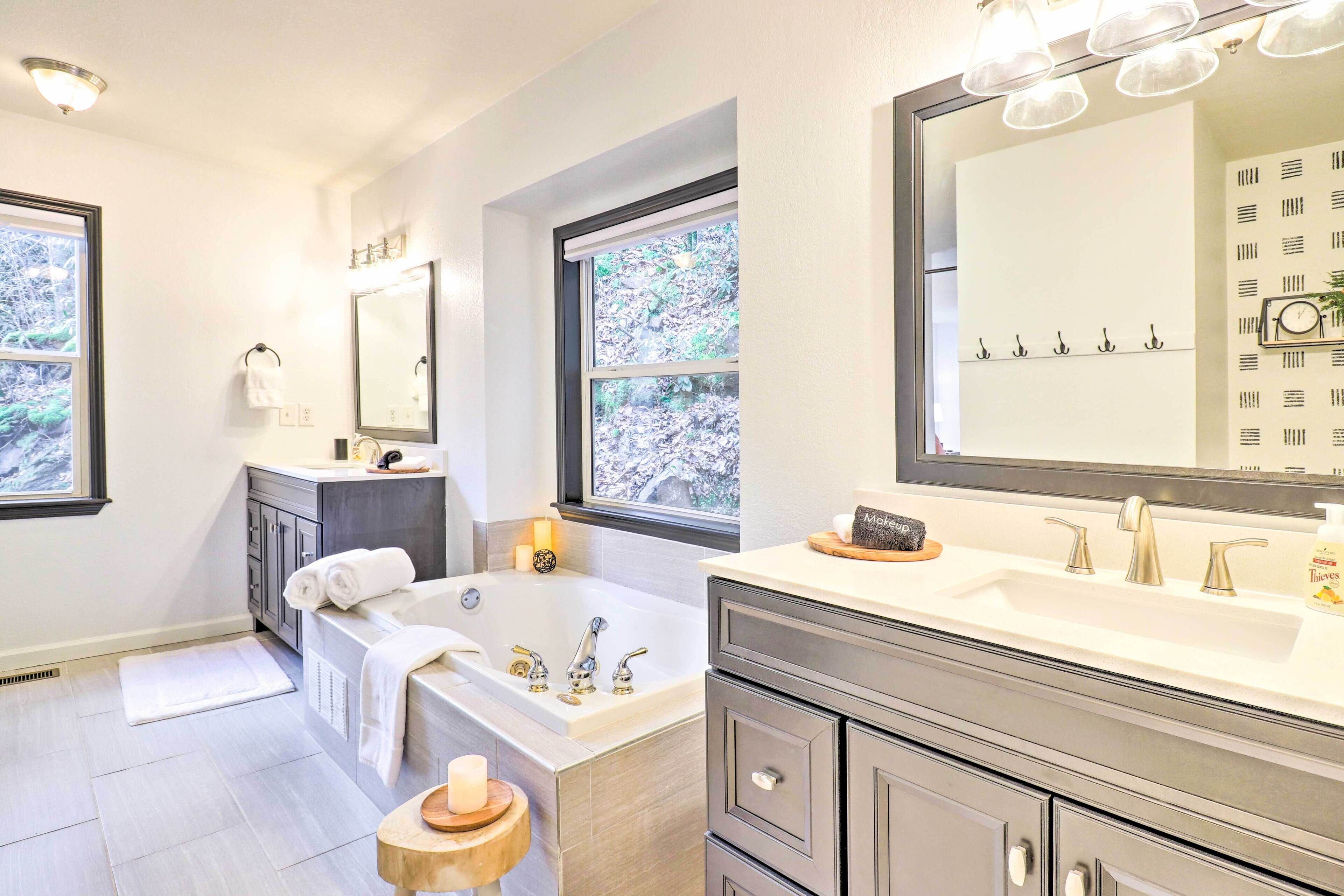 A modern bathroom with a bathtub, two sinks, and a large mirror.
