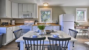 A modern kitchen with white cabinets, a central island, and a dining area with a table set for two. - Scenic Studio w/ Loft & View of the Columbia River (Carson)