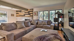 Una sala moderna con un sofá modular, un televisor de pantalla plana y una estantería.