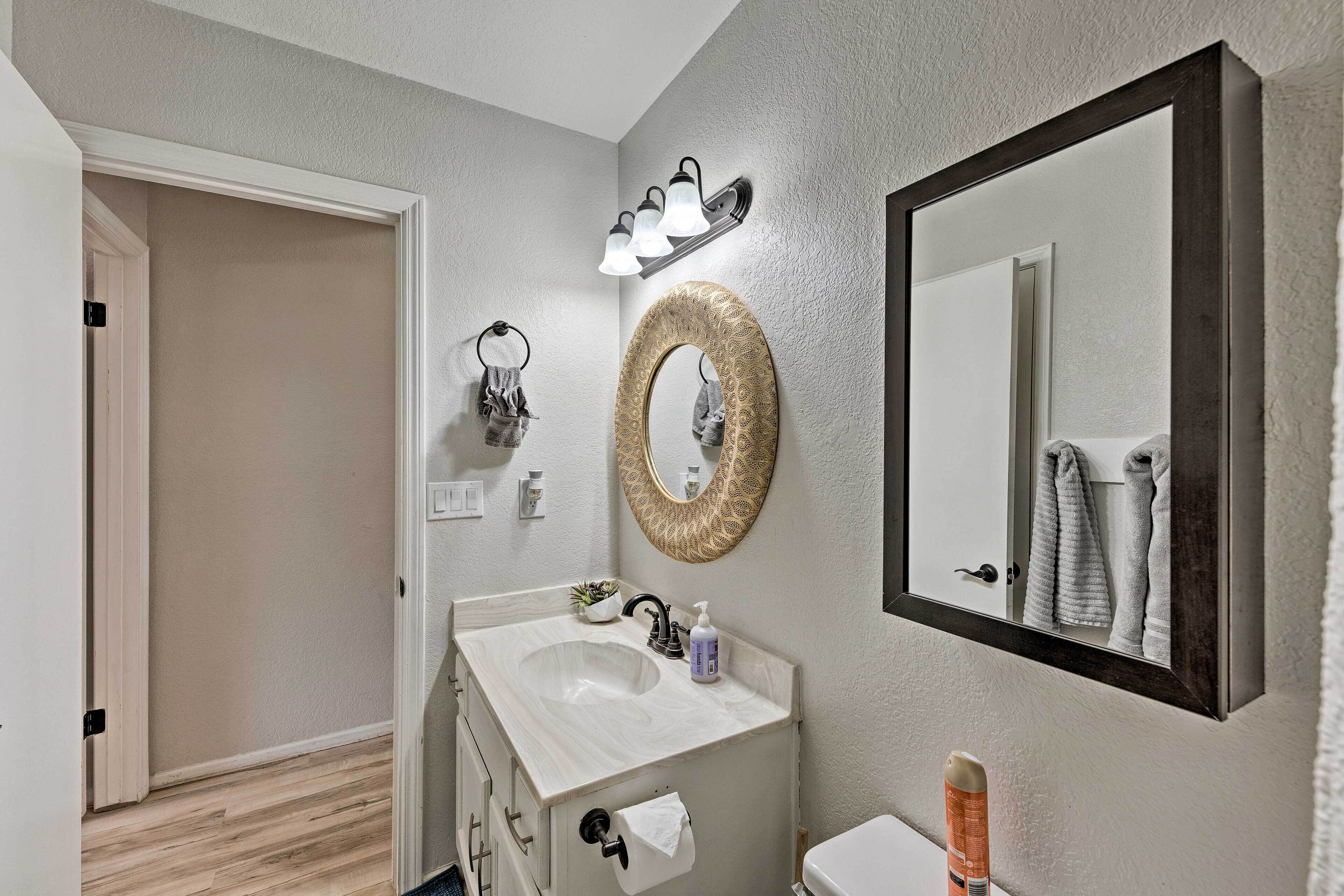 Een badkamer met een witte wastafel, een ronde spiegel en een handdoekhouder.