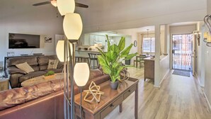 Een moderne woonkamer met een leren bank, een salontafel met een plant en een eethoek op de achtergrond.