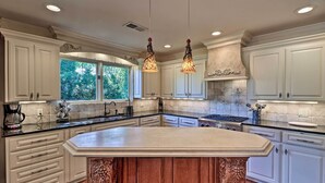 A spacious kitchen with white cabinetry, a large island, and pendant lighting.