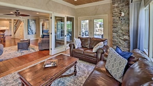 A spacious living room with a brown leather sofa, a wooden coffee table, and a stone accent wall.