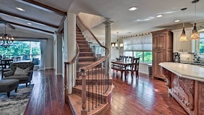A spacious living area with a wooden staircase, a dining area, and a kitchen with a large island.