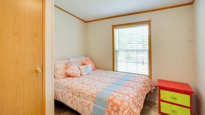 Un dormitorio con cama, ventana, armario y mesita de noche.