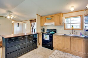 A kitchen with wooden cabinets, a black stove, and a coffee maker. - Lake Texoma Cabin Near Willow Springs Marina! (Mead)