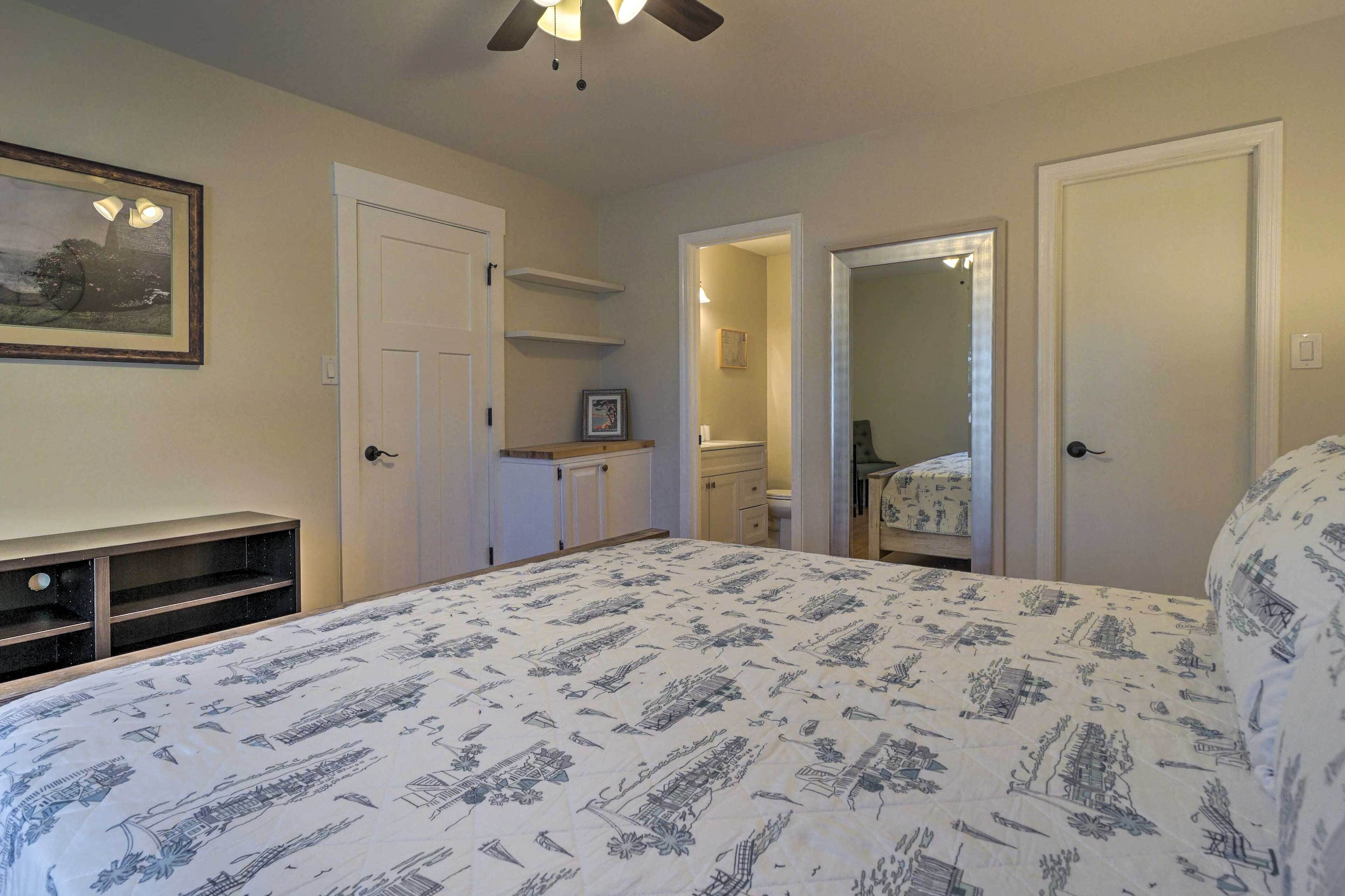 A bedroom with a bed, a dresser, a vanity, and a door leading to another room.