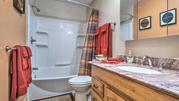 A bathroom with a bathtub, toilet, and vanity with a sink and mirror.