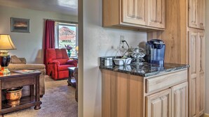 A living room with a red chair, a coffee table with a lamp, and a view of a mountain through a window. - Rural Base Camp for Grand Canyon, Zion & Bryce NP! (Kanab)