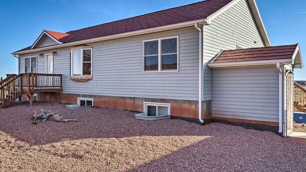 A two-story house with a red roof, a wooden deck, and a gravel driveway. - Rural Base Camp for Grand Canyon, Zion & Bryce NP! (Kanab)