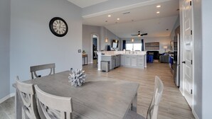 A spacious kitchen with a central island, a dining area with a wooden table and chairs, and a ceiling fan. - Pool & Patio: Newly Constructed Lake Havasu Home! (Lake Havasu City)