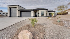 A modern two-story house with a garage, a driveway, and a landscaped front yard with rocks and small plants. - Pool & Patio: Newly Constructed Lake Havasu Home! (Lake Havasu City)