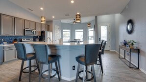 A modern kitchen with a central island, bar stools, and pendant lighting. - Pool & Patio: Newly Constructed Lake Havasu Home! (Lake Havasu City)