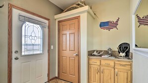 Ein Flur mit einer Holztür, einer Glastür mit Dekor und einem Holzkasten mit Schubladen, sowie einer an der Wand befestigten amerikanischen Flaggen-Dekoration.